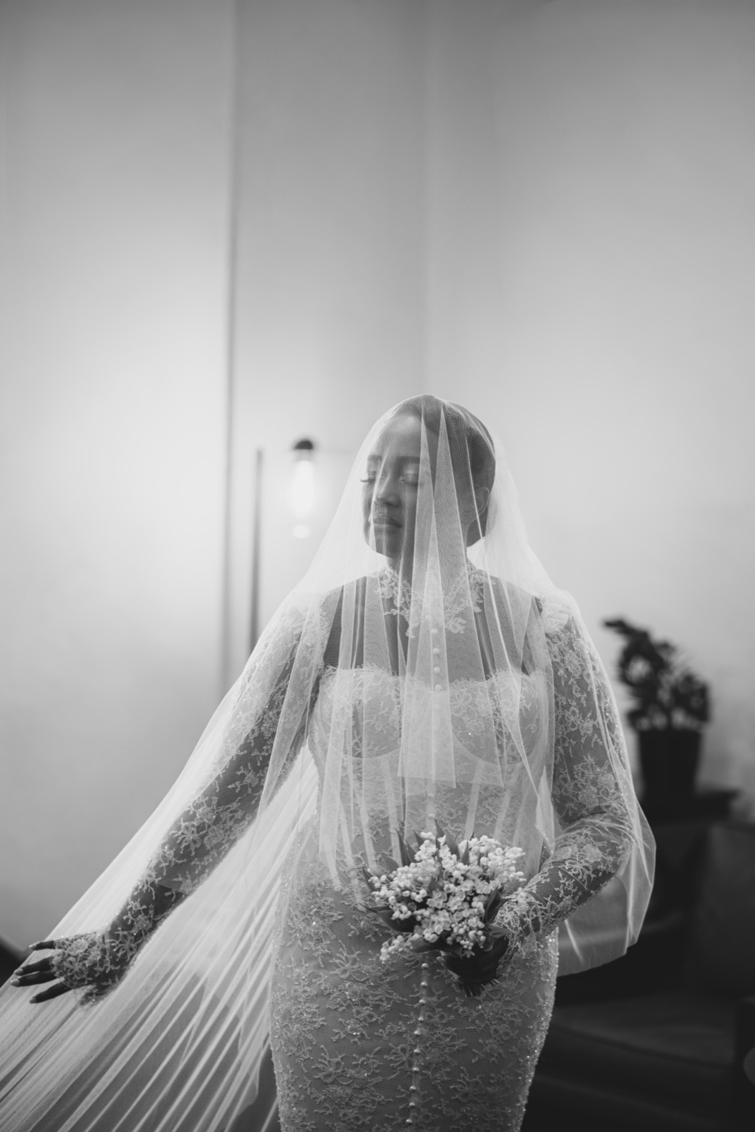 Bride veiled in soft window light holding her bouquet