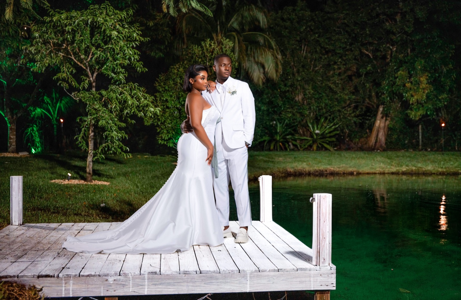 Newlyweds embracing on a waterside dock with flowing veil