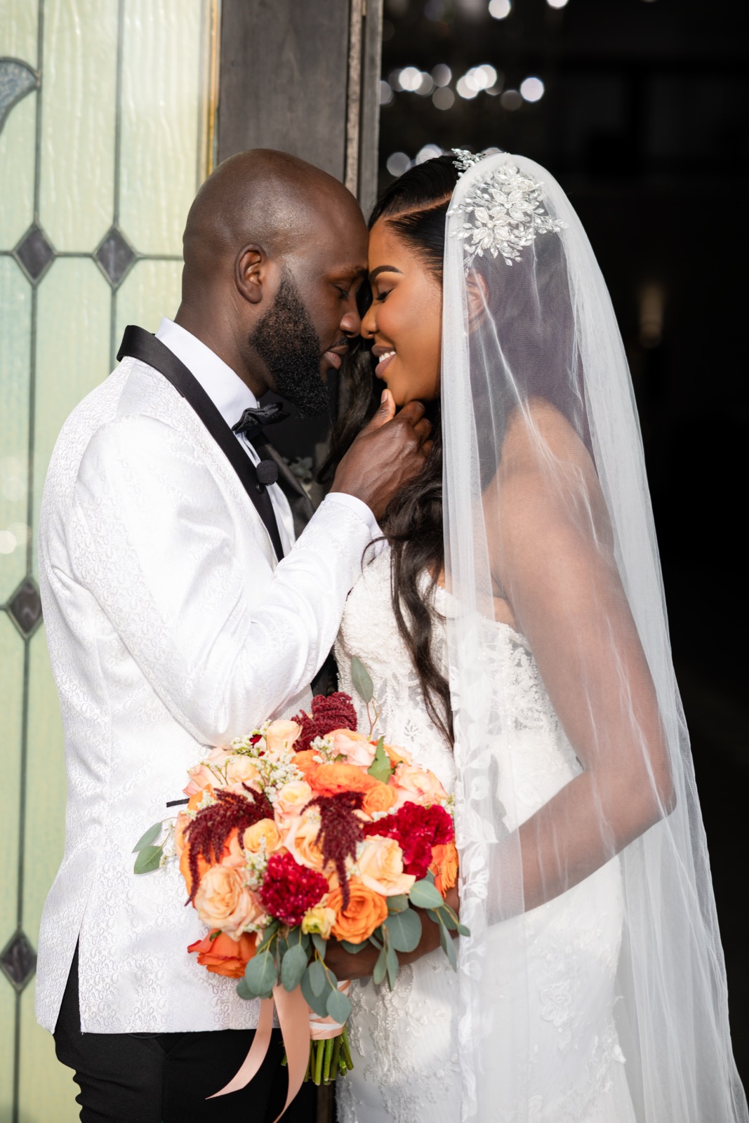 Bride and groom forehead to forehead with a vivid rose bouquet