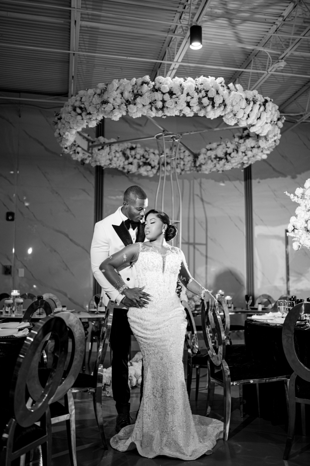 Black-and-white portrait of newlyweds beneath a floral wreath