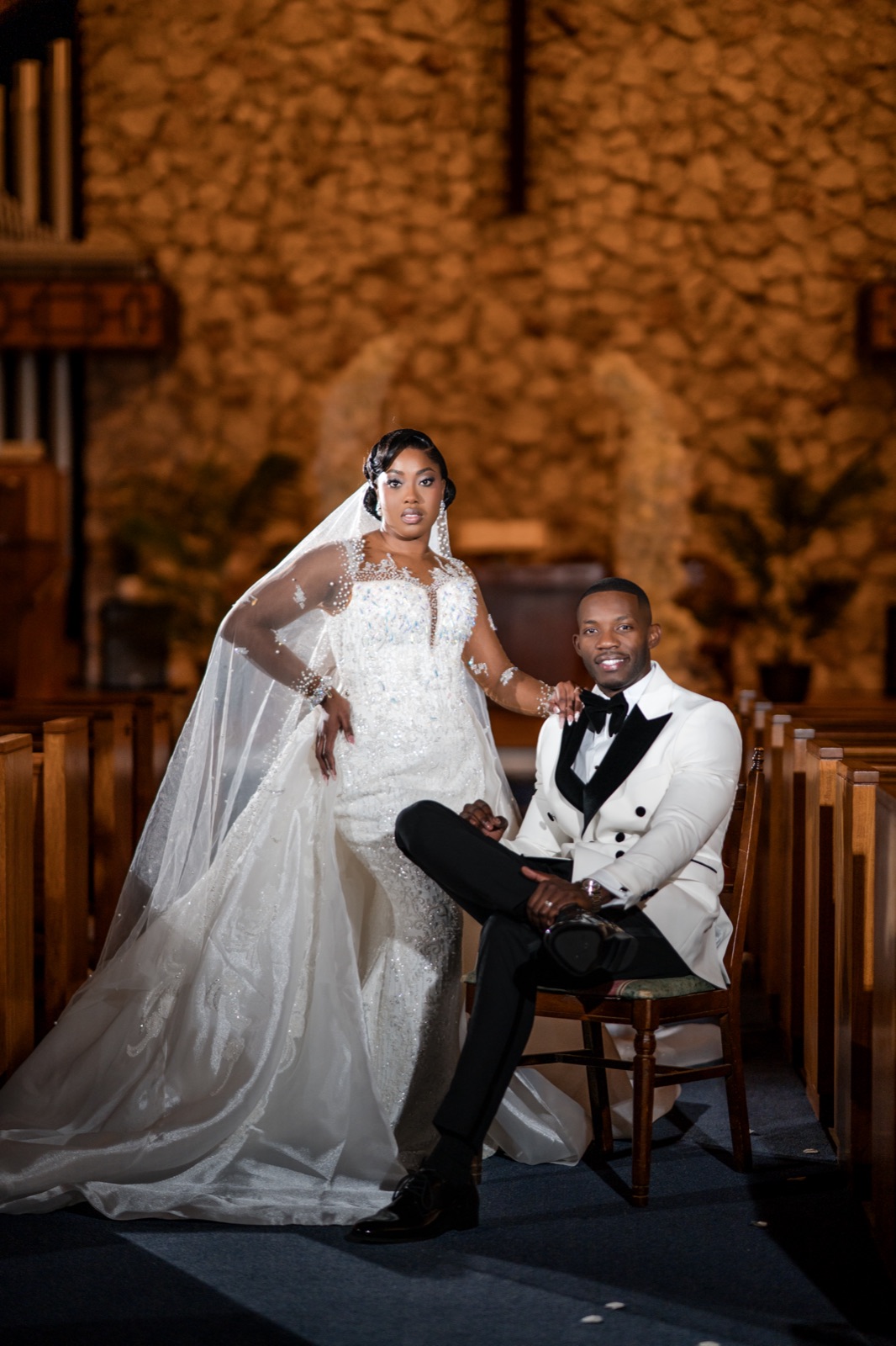 Bride and seated groom framed by warm church arches